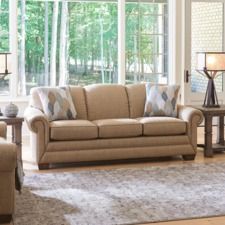 a living room scene with focus on the couch and chair, coffee table and windows