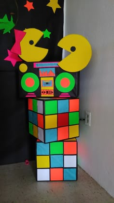 a rubik machine made out of colored paper on the floor next to a wall