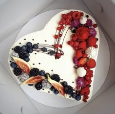 a heart shaped cake decorated with berries, raspberries and strawberries