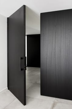 an open black door in the middle of a room with white walls and flooring