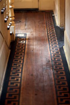 an old wooden floor with black and gold designs on it in a hallway between two walls