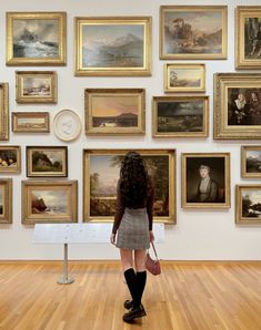 a woman is looking at paintings on the wall