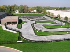 an aerial view of a race track in the middle of a grassy area next to a building