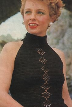 an old photo of a woman wearing a black dress and smiling at the camera with her hands in her pockets