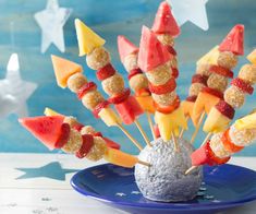 a blue plate topped with watermelon and pineapple skewers next to stars