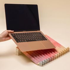 a person holding a laptop in their left hand and several colored folders stacked on top of each other