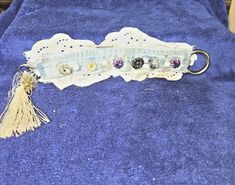 an old key chain with buttons and tassels is laying on a blue towel