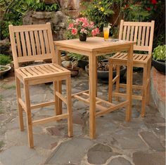 two wooden chairs sitting next to each other on a stone patio with flowers in the background