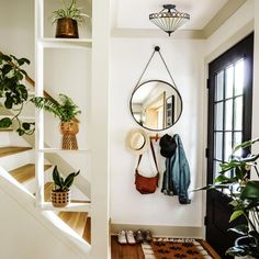 there is a mirror, coat rack and plants on the wall in this entryway