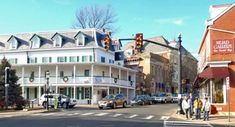 people are standing on the sidewalk in front of some buildings and traffic lights at an intersection