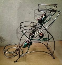 a metal rack with flowers on it sitting on a table next to a gray wall