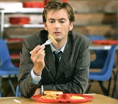 a man sitting at a table with a fork in his mouth