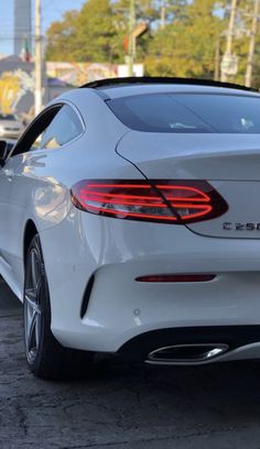 the rear end of a white car parked in a parking lot