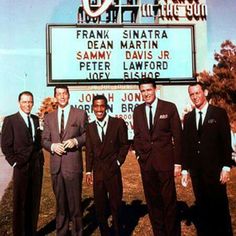 four men in suits standing next to each other near a sign that says frank shanata dean martin sammy davis jr peter lawford joey