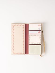 a pink and white planner book with notes in it on top of a white surface