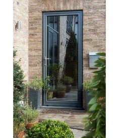 an open door to a brick building with potted plants