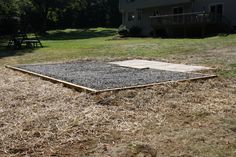 an empty yard in front of a house with grass on the ground and a picnic table next to it