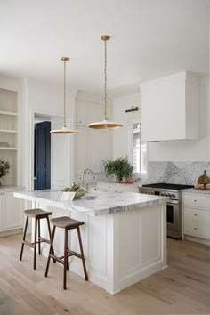 a kitchen with two stools in front of an island and marble counter tops on the other side