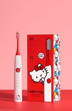 an electric toothbrush next to a hello kitty book on a pink background with the box