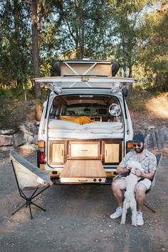 a man and his dog sitting in the back of a van