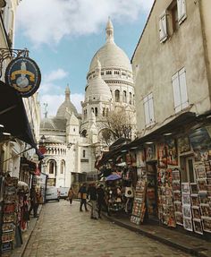 people are walking down the street in front of some buildings with domes on them and shops near by