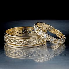 two gold wedding bands with diamond accents on a reflective surface in front of a black background