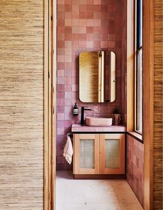 a bathroom with a sink, mirror and wooden cabinetry in it's corner