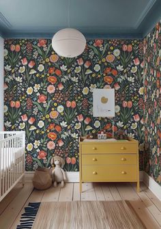 a baby's room with floral wallpaper and yellow dresser in the foreground