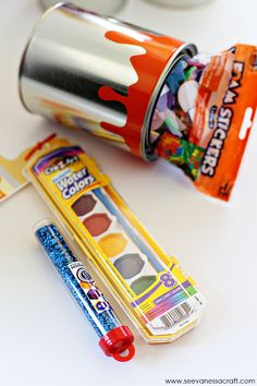 an orange and white cup next to a tube of paint with some candy in it