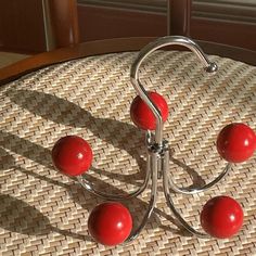 three red balls sitting on top of a metal stand next to a window sill