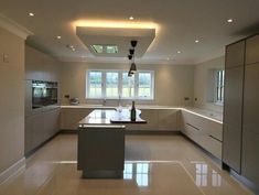 an empty kitchen with stainless steel appliances and counter tops is shown in this image, there are lights on the ceiling