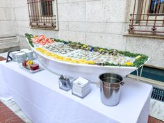 a large platter of food on top of a white table with silver buckets