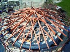 a large wooden structure being constructed on top of a cement slab with scaffolding around it