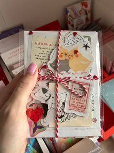 a hand holding an open gift box with stickers and tags attached to the inside