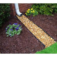 a garden with mulch and flowers in the ground next to a house door way