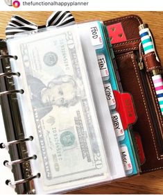 an open wallet with money inside it on top of a wooden table next to a notepad