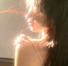 a woman with her hair blowing in the wind and sunlight shining down on her face