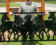 a man standing in front of a gate with horses on it