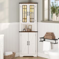 a bathroom with white walls and wood flooring is shown in this image, there are towels on the shelf next to the cabinet