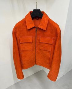 an orange jacket hanging on a white wall