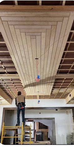 two men are working on the ceiling in an unfinished room that is being built with wood planks