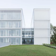 two large white buildings sitting next to each other on top of a lush green field