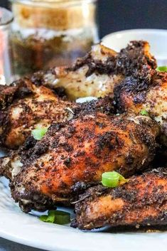 some fried chicken on a white plate with sauce and seasoning next to the food