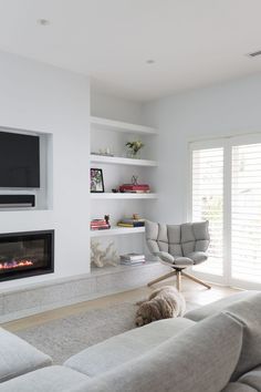 a living room filled with furniture and a flat screen tv mounted on the wall above a fire place