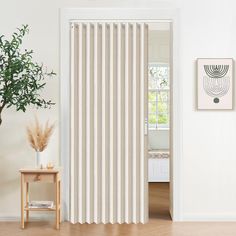 a white and beige striped curtain hanging on a wall next to a potted plant