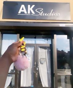 a person is holding a fake banana in front of a storefront door with the words ak studios on it