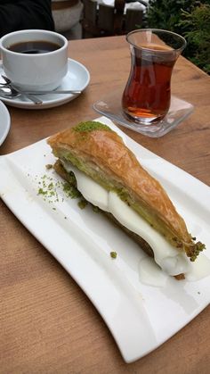 a pastry on a white plate next to a cup of tea and a glass of water