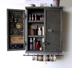 an open cabinet with jewelry hanging from it's sides and two shelves on the wall