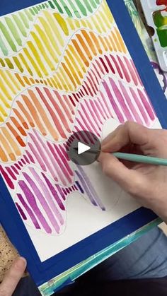 a person is painting with watercolors on a piece of paper that has been placed in front of them