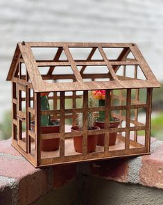 a small wooden house shaped like a greenhouse with potted cacti and succulents in it